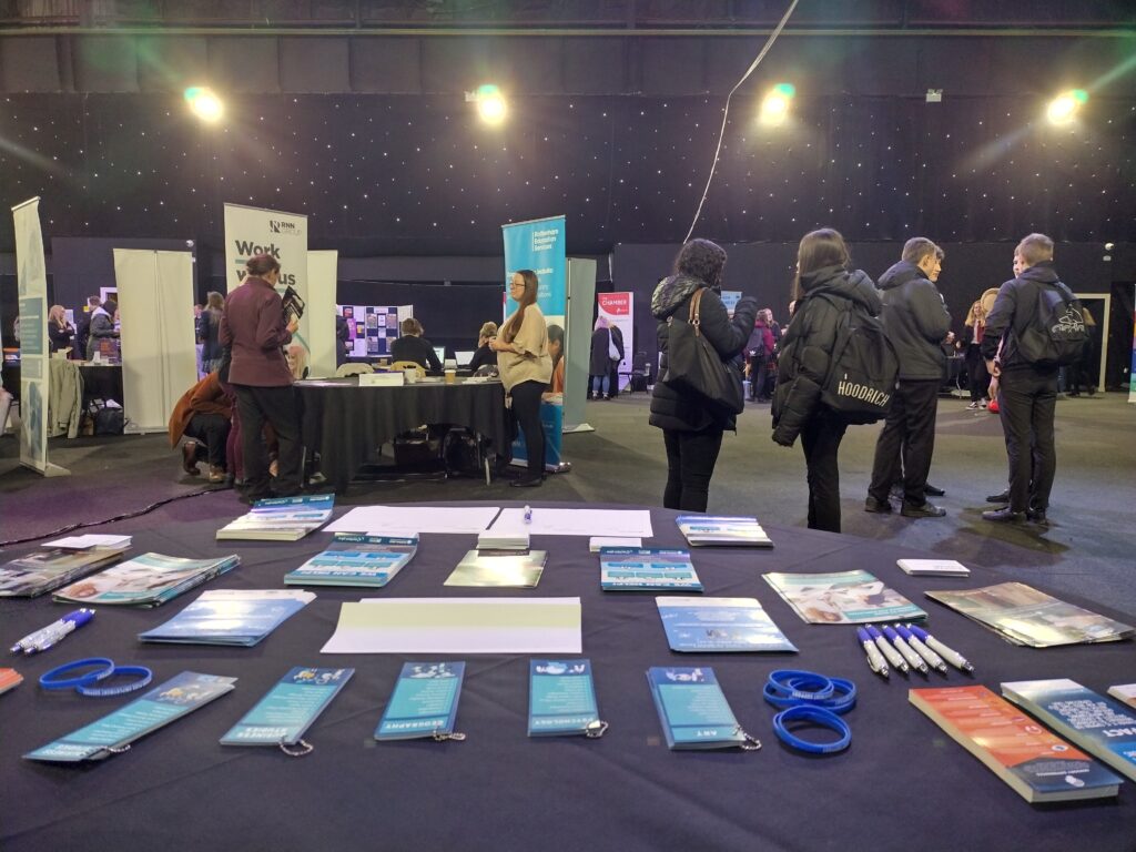 an image looking out from behind a table at an event we had a stall at. The table has leaflets and some training items on the table