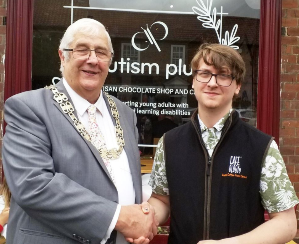 Image of chairman of North Yorkshire council with a big gold chain on shaking hands with Jack an autistic gentleman