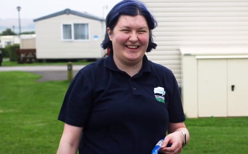 picture of a lady smiling showing her waist upwards stood in front of caravans