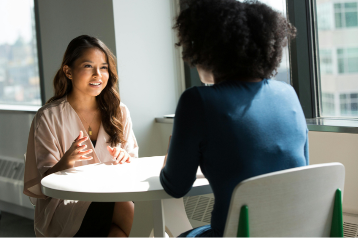 2 people having a chat, sat at a table
